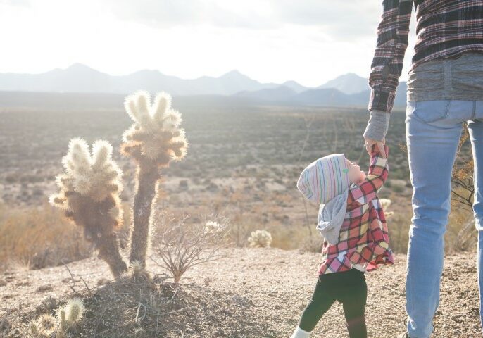 A single Mom holding her child's hand in the desert